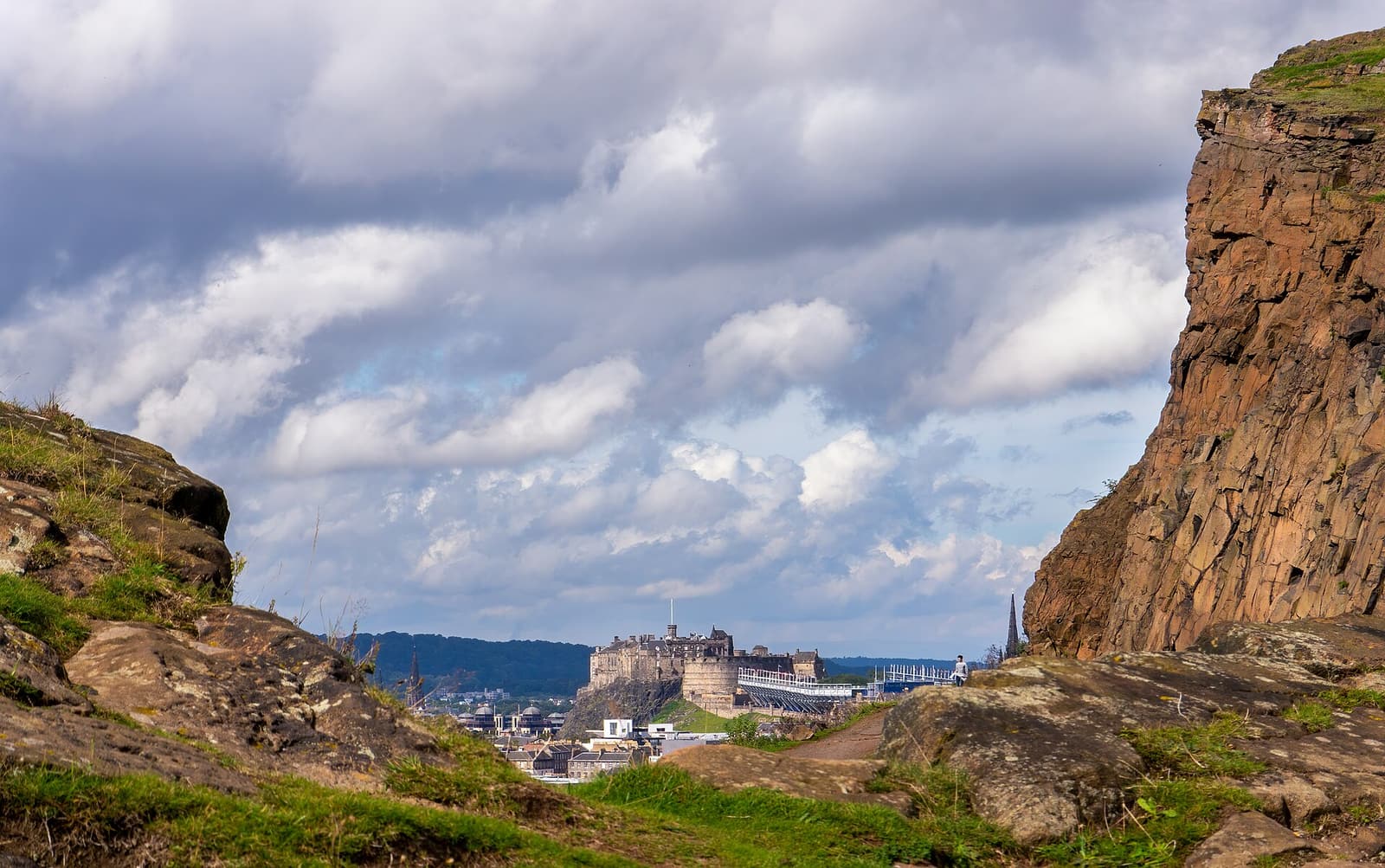 The cliffs of Salisbury Crags in Holyrood Park, with Edinburgh Castle in the distance