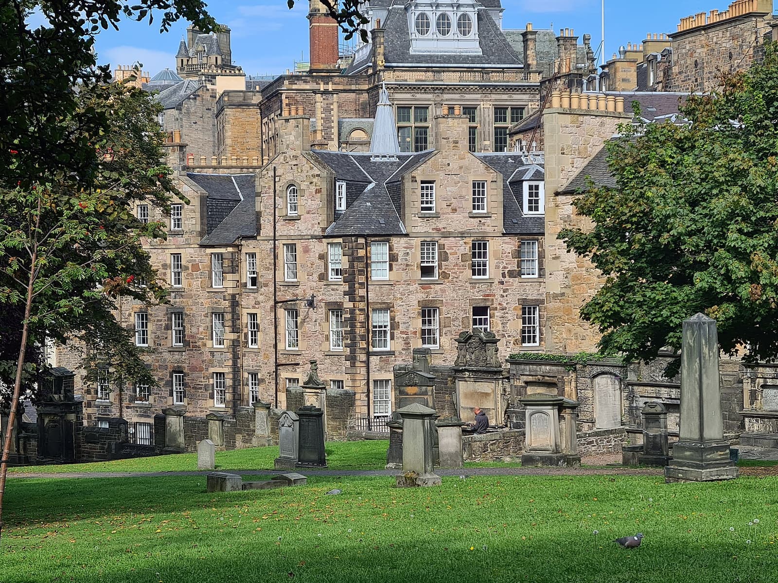 Old gravestones on the grass of Greyfriars Kirkyard, backed by tall Old Town tenements